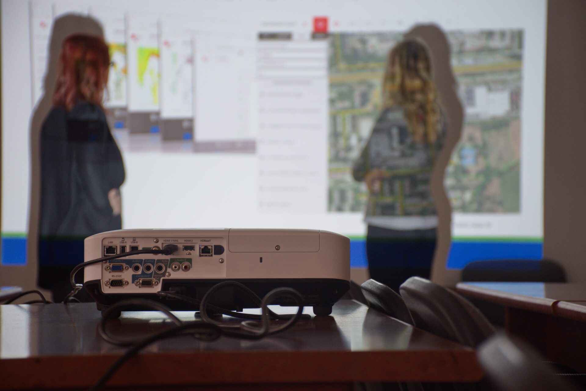 Colleagues standing by projection screen on wall during meeting