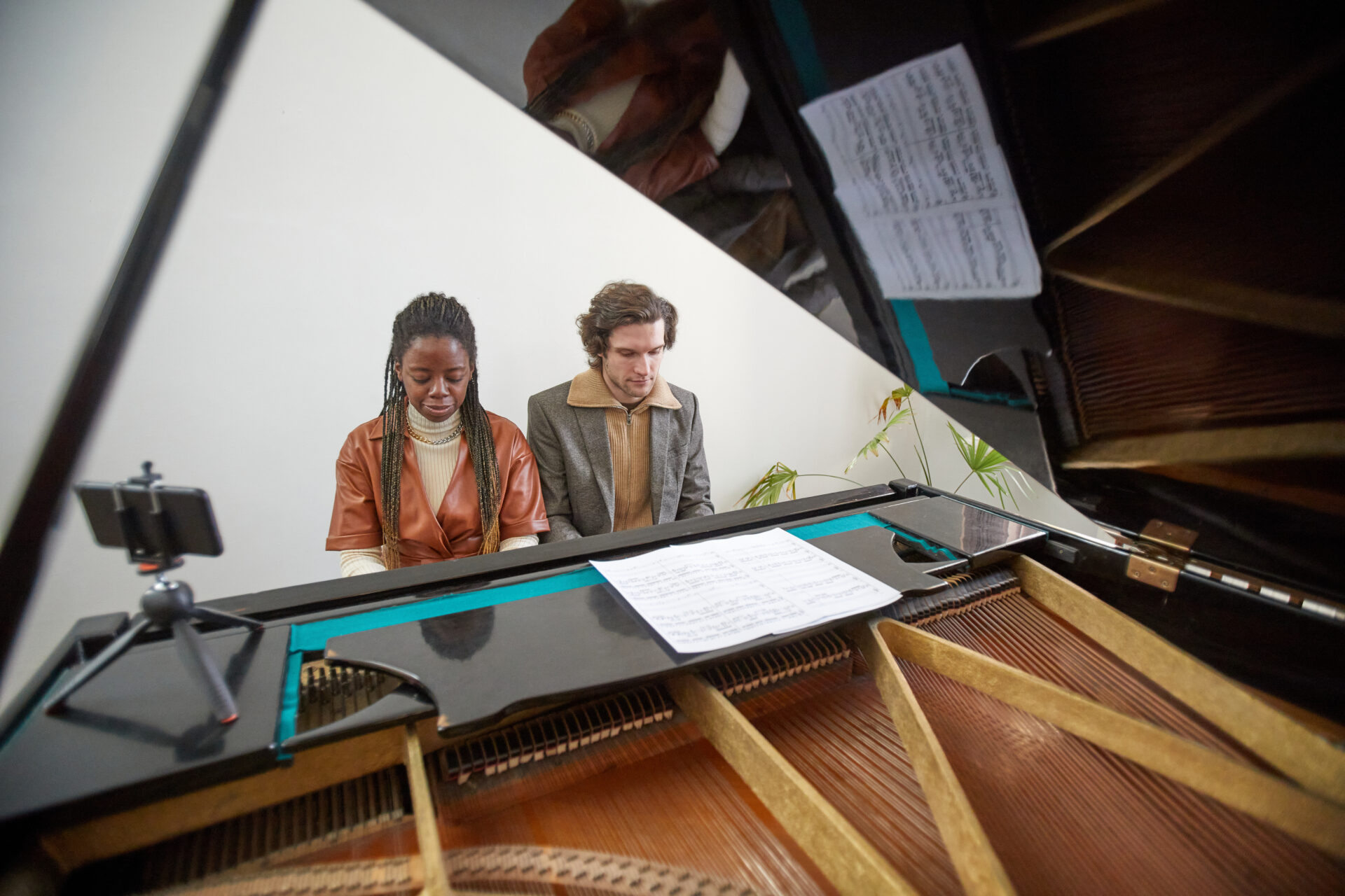 Young couple playing the piano in team